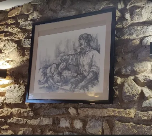 Dibujo a carboncillo enmarcado sobre la pared de piedra del comedor.