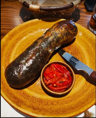 Morcilla de Maeztu asada con pimientos de Leiva en plato de cerámica.