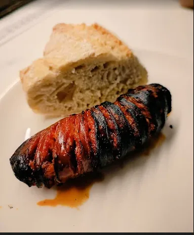 Txorizo tostado y abierto, con un trozo de pan.