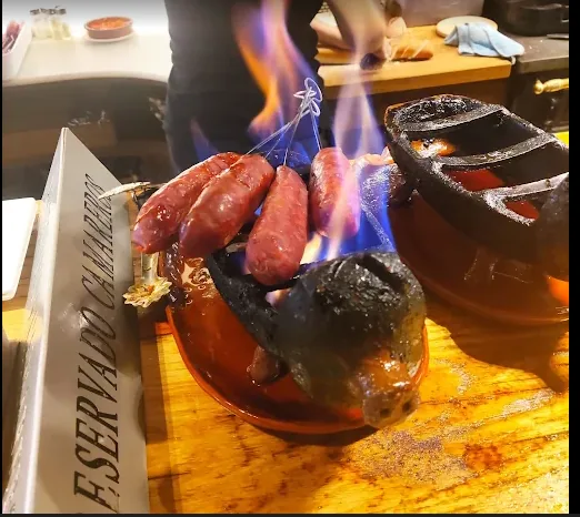 Txorizos al infierno flameados sobre cerditos de barro en la barra.