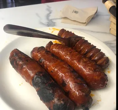Plato de txorizos tostados sobre una mesa de mármol.