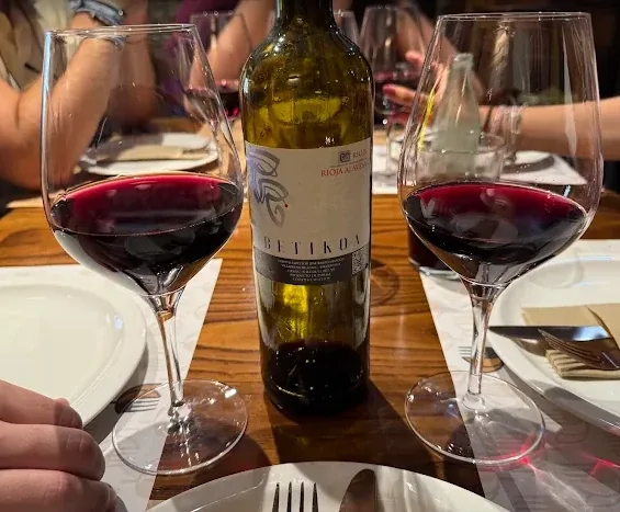 Botella de vino de Rioja Alavesa con dos copas servidas sobre la mesa.